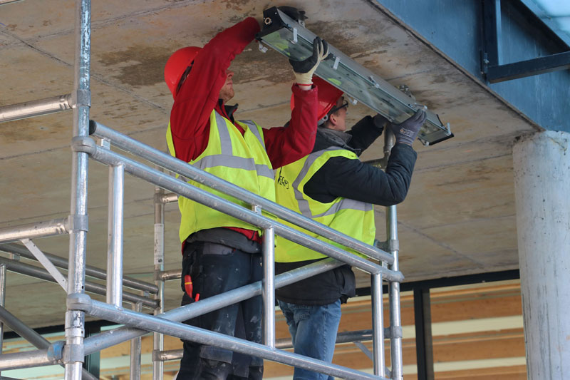 Installation de luminaire LED sous le préau d'un collège